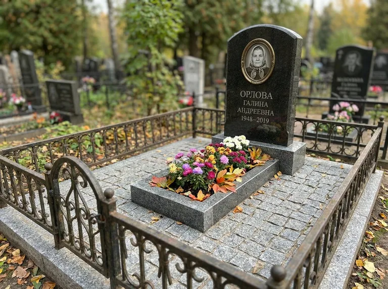 Благоустроенное захоронение с гранитной плиткой, оградой и цветником в Калининграде