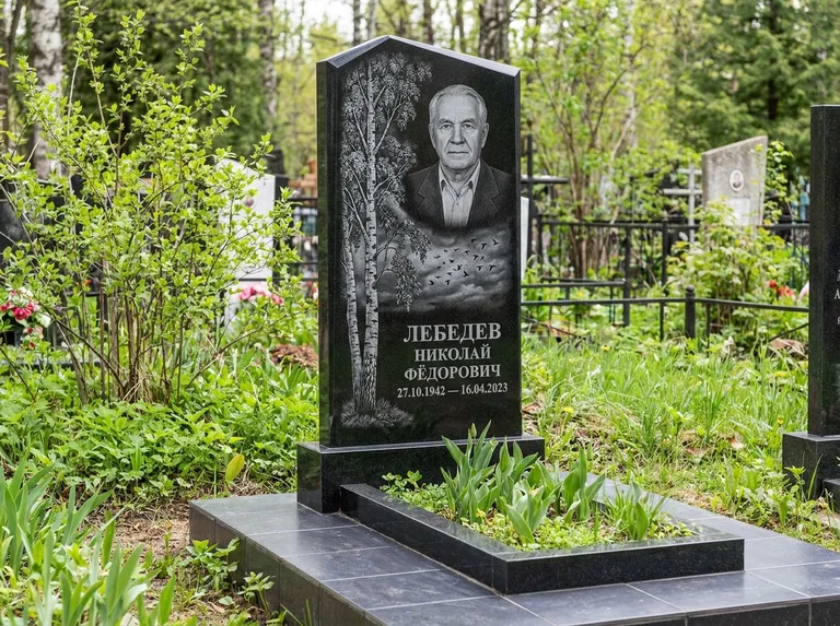 Памятник с гравировкой берёзы: вертикальная стела со скошенным верхом — берёза и стая птиц в небе, гранитный цоколь с тёмной плиткой, работа «Лебедев» в Калининграде