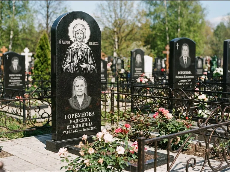 Памятник с гравировкой иконы: стела с арочным верхом и киотом под образ — гравировка образа Матроны Московской, гранитный цоколь с тёмной плиткой, работа «Ковалёв» в Калининграде