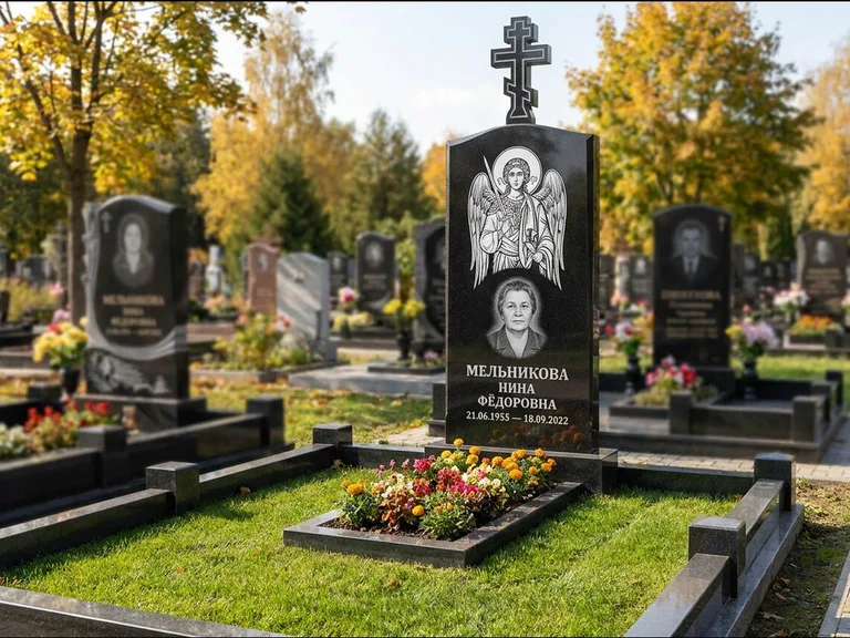 Памятник с гравировкой иконы: округлая стела-медальон с ликом — гравировка Богородицы «Семистрельная», луговые травы и полевые цветы за участком, работа «Гущин» в Калининграде