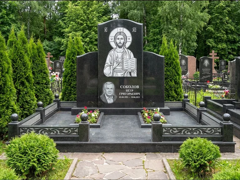 Памятник с гравировкой иконы: широкая горизонтальная лежачая плита-стела — икона в резной рамке-киоте, серая гравийная отсыпка с бордюром, работа «Богданова» в Калининграде