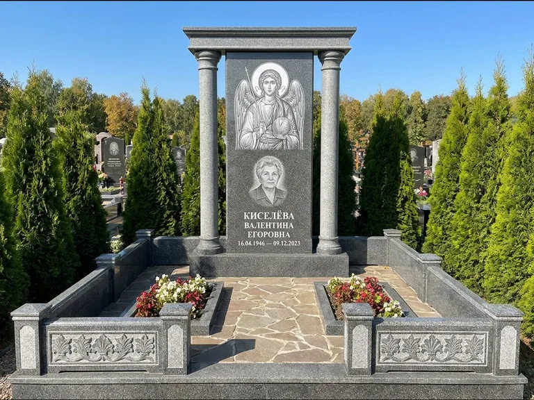 Памятник с гравировкой иконы: массивная стела с двускатным навершием-домиком — гравировка Николая Чудотворца, живая изгородь из туи, работа «Журавлёв» в Калининграде