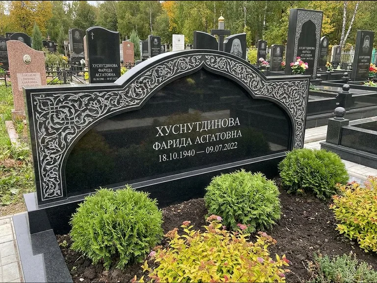 Мусульманский памятник: вытянутая горизонтальная семейная стела с аркой — белая гравировка силуэта мечети с минаретами, участок с декоративными кустами, работа «Зарипова» в Калининграде
