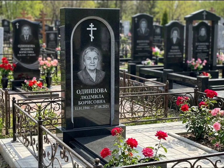 Памятник из чёрного гранита — скромная невысокая стела с крестом с терновым венцом, работа «Лаврентьева» в Калининграде