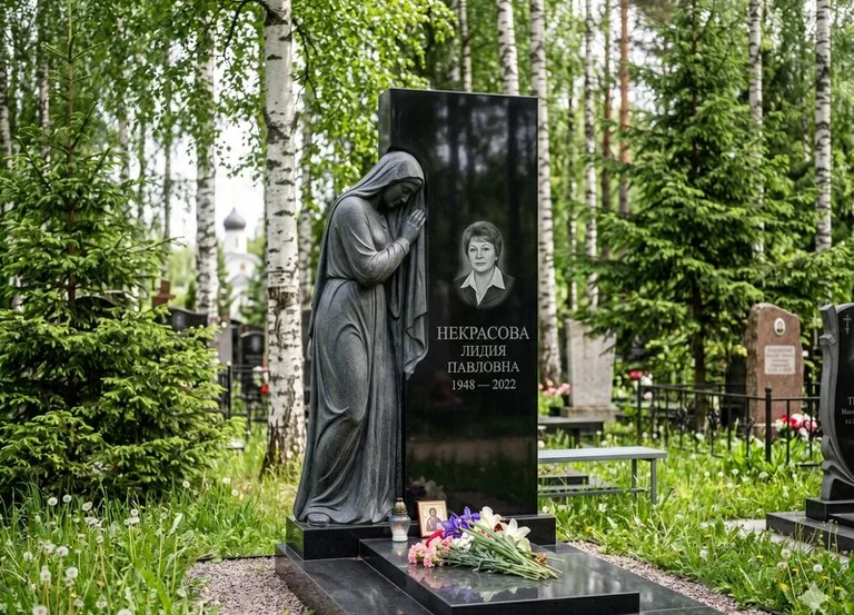 Гранитная фигура скорбящего мужчины у чёрной стелы в Калининграде